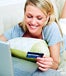 Woman lying on the couch shopping with credit card online 