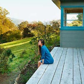 Woman sitting on deck looking at the view | Trinette Reed/Getty Images