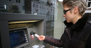 Woman taking cash from outdoor ATM © jean schweitzer/Shutterstock.com