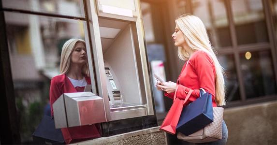 Types of banks: Are you banking at a thrift, bank or credit union? Woman walking up to ATM | eclipse_images/Getty Images