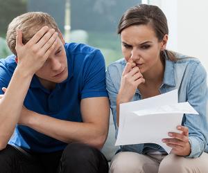 Young couple in living room analyzing bills © Photographee.eu/Shutterstock.com 
