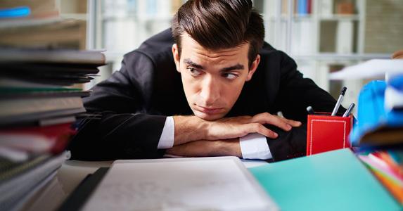 Survey: Few workers anticipating a bonus or boost in pay Young male office employee sitting bored at work © iStock