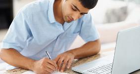 Young man writing notes at desk © Yuri Arcurs - Fotolia.com