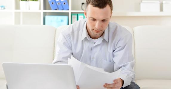 A dozen deductions for your small business Young man reading documents in small office | iStock.com/elenaleonova