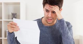 Young man looking at paper in panic © Andrey_Popov/Shutterstock.com