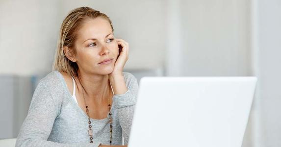 Where can I go to get an unsecured loan? Young woman on grey sweater sitting at home | iStock.com/kupicoo