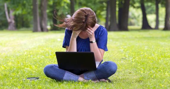 Young woman sitting in park holding her head © Action Sports Photography/Shutterstock.com