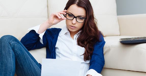 Young woman wearing glasses and reading paperwork © baranq/Shutterstock.com