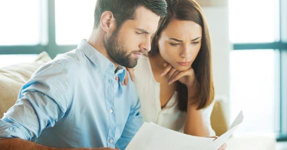 Younger couple looking over paperwork together | iStock.com