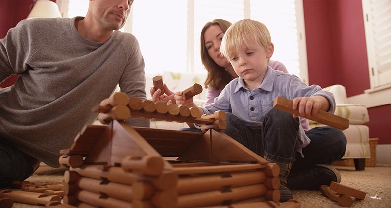 Parents building wooden cabin with child | Rocketclips, Inc./Shutterstock.com